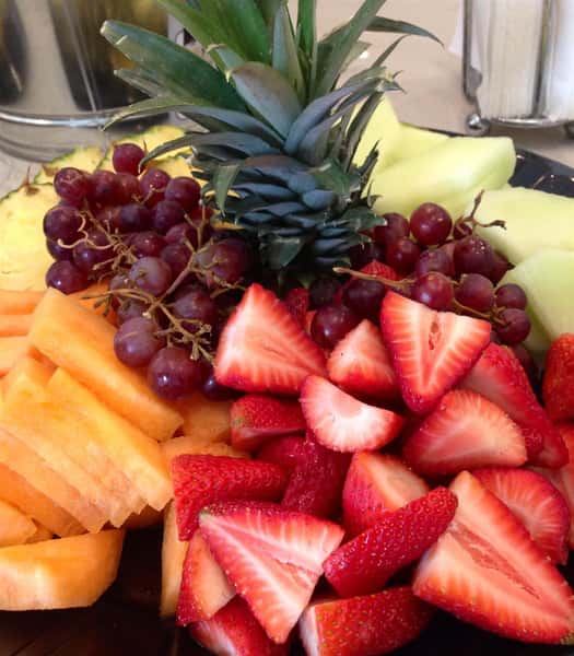 catering display of sliced strawberries, honeydew melon, cantaloupe, red grapes and pineapple