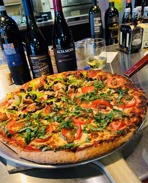 1/2 Margherita Pizza & 1/2 Veggie Pizza with an aossortment on Wine bottles