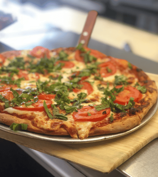 Margherita Pizza topped with basil on a pizza pan