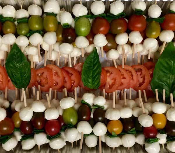 catering display of tomatoes and mozzarella on skewers topped with basil leaves