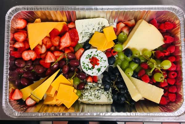 A foil tray filled with Strawberries, Grapes, Blueberries, Raspberries and assortment of Cheese