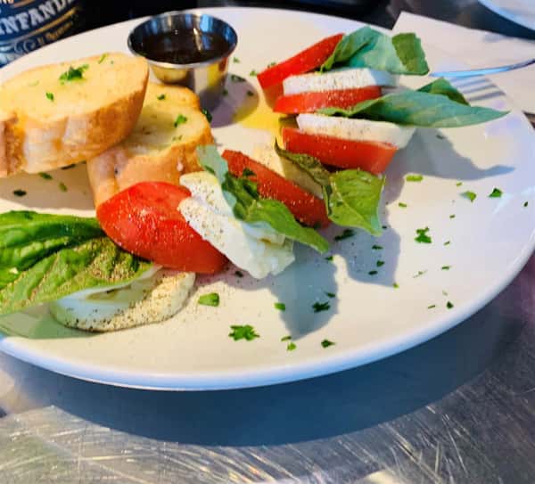 Mozzarella di bufala, Roma tomato, basil, extra virgin olive oil and balsamic vinegar on a plate