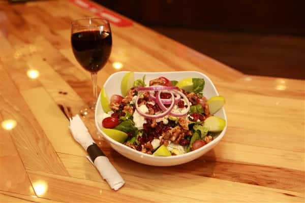 Apple Walnut Salad with red wine on the side on a wooden table.