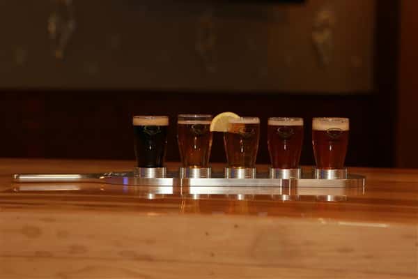 Side view of a flight of 5 beers on a wooden bar top
