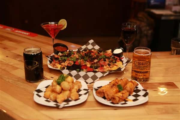 Colby cheese curds, Tatchos, and Bavarian Pretzel Sticks with a glass of red wine, a red martini with a lime slice, a dark beer and a light beer.