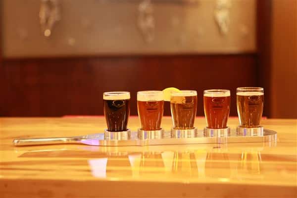 Side view of a flight of 5 beers on a wooden bar top