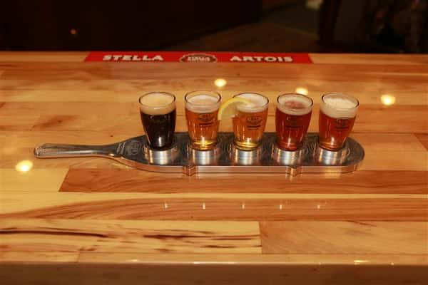 Top view of a flight of 5 beers on a wooden bar top