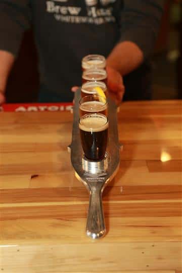 Front view of a flight of 5 beers on a wooden bar top