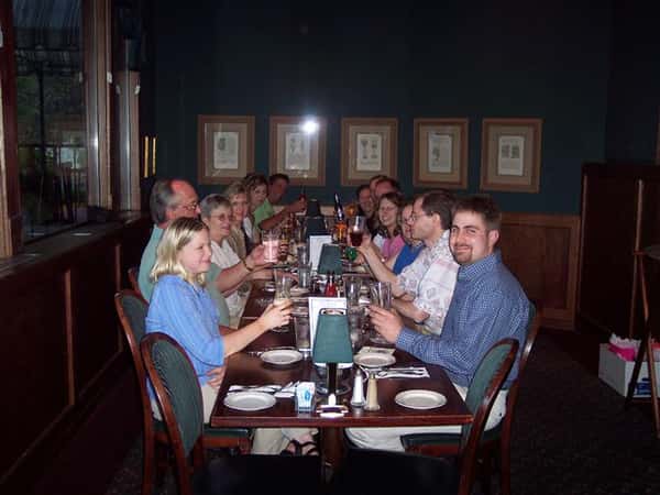 Group of about 13 guests at dining table raising their glasses.