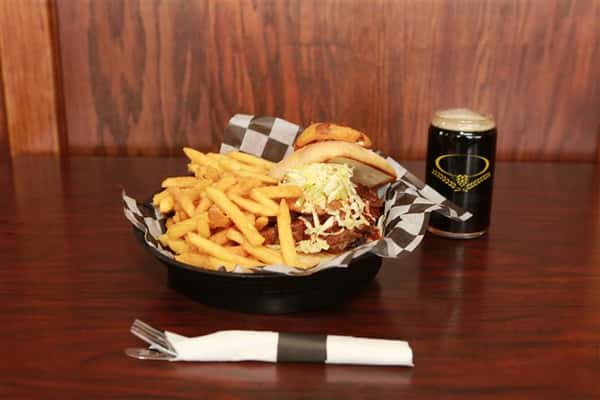 Brew House Specialty Sandwich topped with coleslaw with a side of french fries. Served with a dark beer.