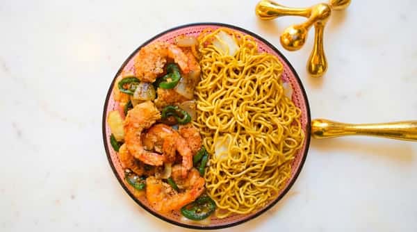 Bowl of salt and pepper shrimp with noodles and vegetables, photographed from above.