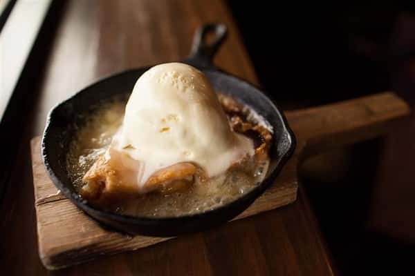 pie in a skillet topped with a scoop of ice cream