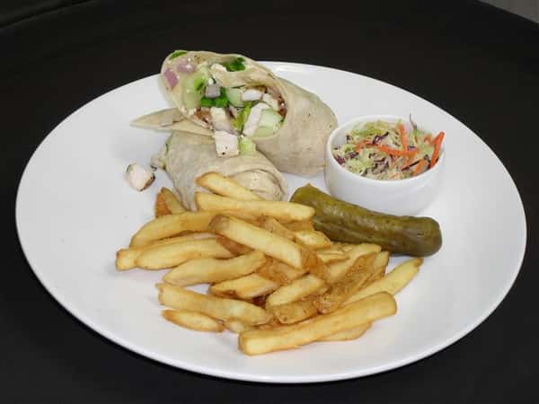wrap with a variety of ingredients with a side of french fries, pickle spear and cole slaw