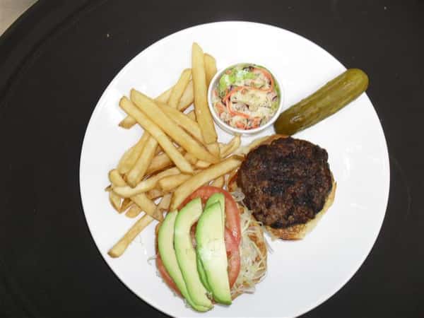 hamburger open faced with shredded lettuce, tomato slices and avocado slices with a side of french fries, pickle spear and cole slaw