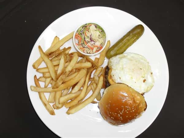 hamburger with cheese, fried egg and a side of french fries, pickle spears and cole slaw