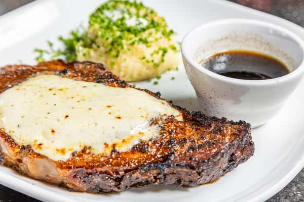 Black and bleu prime rib topped with melted cheese and served with mashed potatoes and au jus