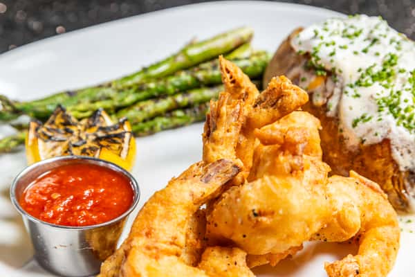 Crispy tempura shrimp with loaded baked potato, asparagus, and dipping sauce at Gorat's Steak House