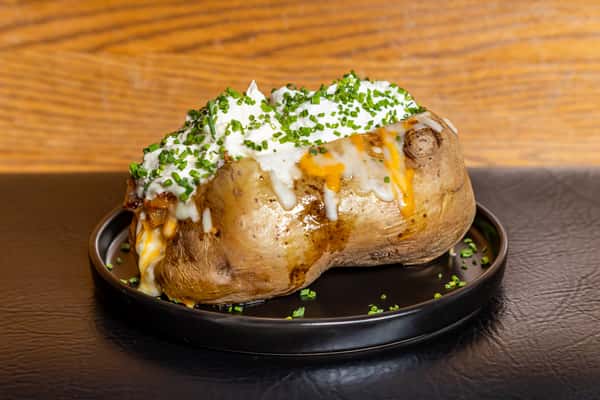Loaded baked potato topped with sour cream, cheese, and fresh chives at Gorat's Steak House