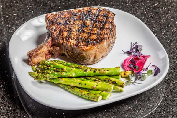 Chargrilled cowboy ribeye with asparagus and steakhouse garnish at Gorat's Steak House