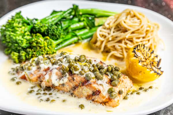 Salmon piccata with broccolini, pasta, capers, creamy sauce, and grilled lemon at Gorat's Steak House