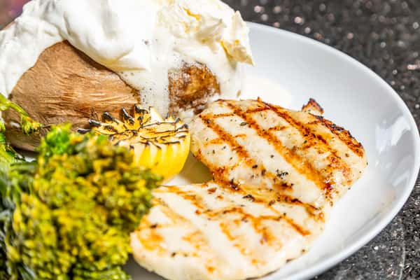 Grilled chicken breast with broccolini, loaded baked potato, and charred lemon at Gorat's Steak House