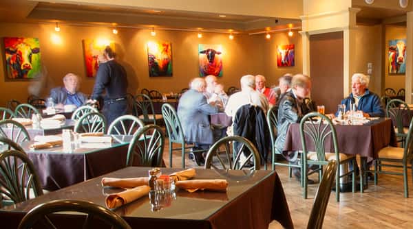 Restaurant dining room with patrons, a waiter, and art on the walls.
