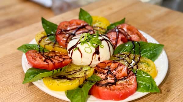 Tomato and mozzarella salad with red and yellow tomatoes, basil, and balsamic glaze.