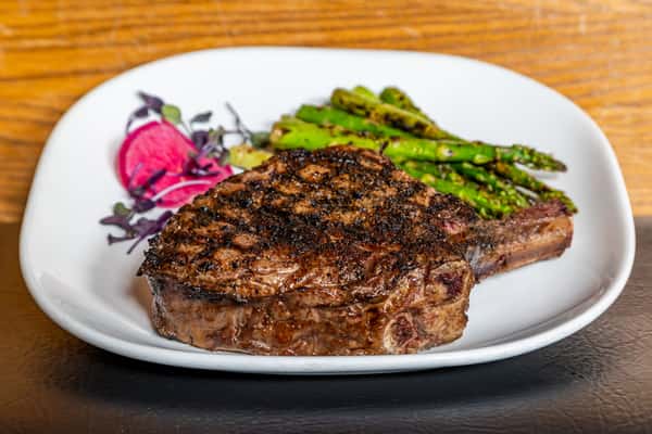 Chargrilled cowboy ribeye with asparagus and steakhouse garnish at Gorat's Steak House