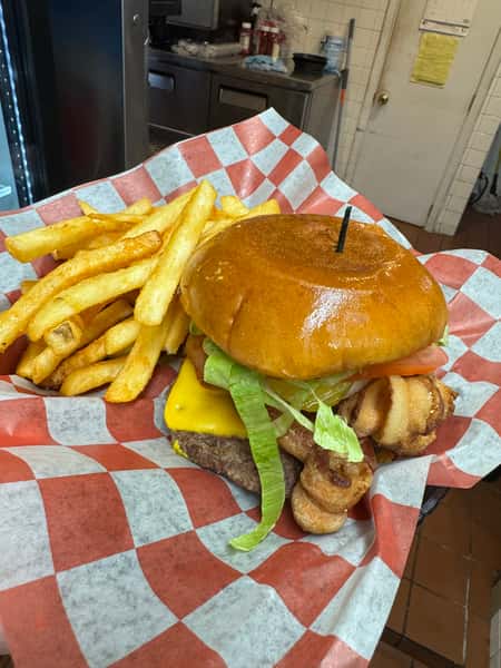A large cheeseburger with two beef patties, melted cheese, lettuce, and onions, served with crinkle-cut fries in a basket.