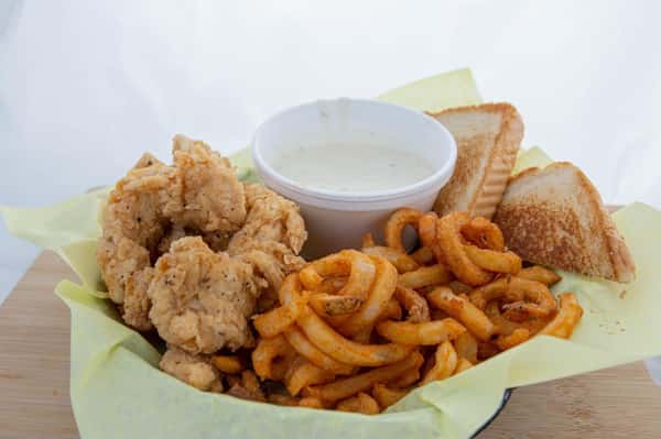 Basket of fried chicken tenders, seasoned curly fries, toasted bread slices, and a cup of ranch dipping sauce on yellow paper.