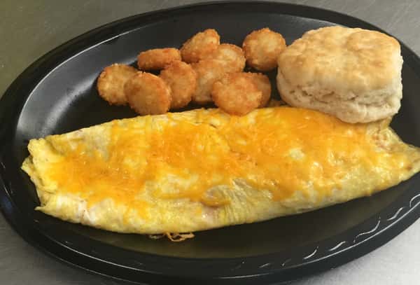 Cheese omelet served with crispy tater tots and a fluffy biscuit on a black plate.