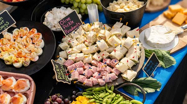 Selection of party appetizers including pinwheel wraps, ham roll-ups, deviled eggs, and cheese.
