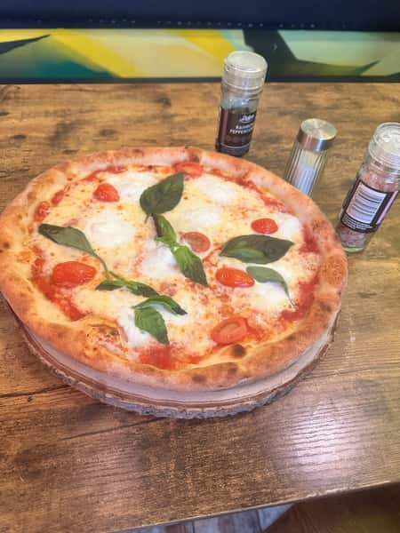 Classic Margherita pizza with fresh mozzarella, tomato sauce, cherry tomatoes, and basil on a rustic wood-fired crust