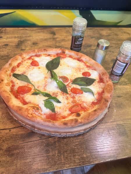 Classic Margherita pizza with fresh mozzarella, tomato sauce, cherry tomatoes, and basil on a rustic wood-fired crust