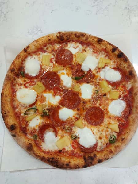 Wood-fired pepperoni and pineapple pizza with melted mozzarella, fresh jalapeños, and a blistered crust