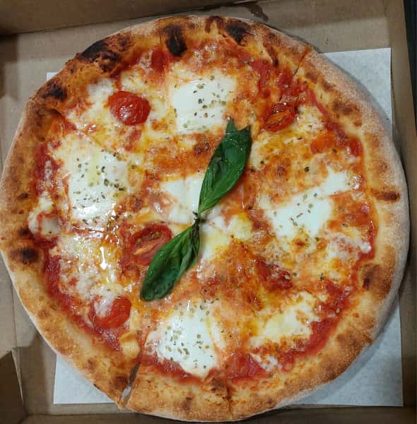 Wood-fired Margherita pizza with melted mozzarella, cherry tomatoes, fresh basil, and blistered crust in a takeout box