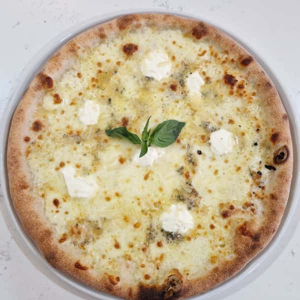 Four cheese pizza with melted mozzarella, gorgonzola, ricotta, and parmesan, finished with fresh basil on a wood-fired crust