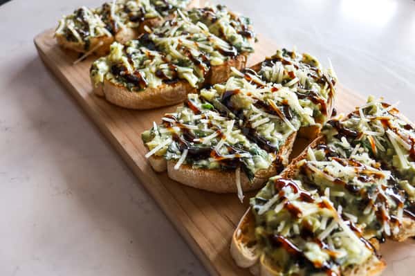 Catering - Spinach and artichoke spread bruschetta topped with parmesan cheese and balsamic glaze