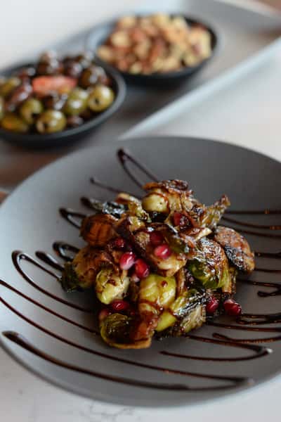 plate of Brussels sprouts and warm olives on a plate behind