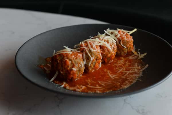 plate with one skewer of meatballs and sauce