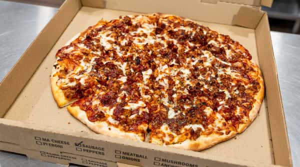 Meat pizza with melted cheese and a thick crust in a cardboard box.