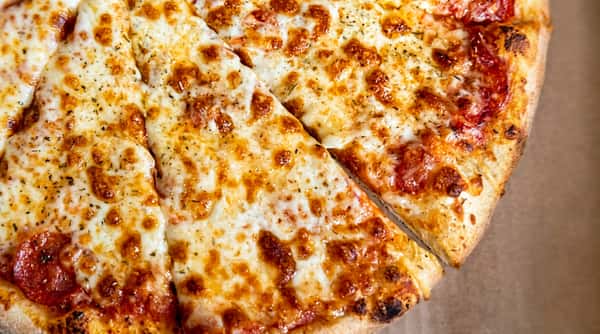 Pizza with melted mozzarella cheese, red sauce, and herbs, cut into slices.