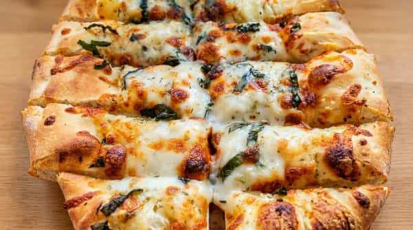 Cheesy breadsticks topped with melted mozzarella, baked herbs, and basil cut into long strips.