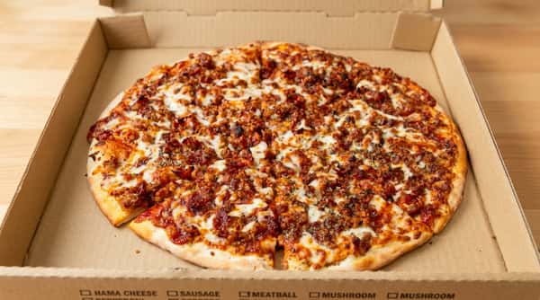 Meat pizza with melted cheese and a thick crust in a cardboard box.