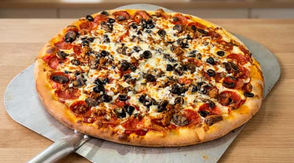 Pepperoni and sausage pizza with mushrooms, black olives, and melted mozzarella on a pizza peel.