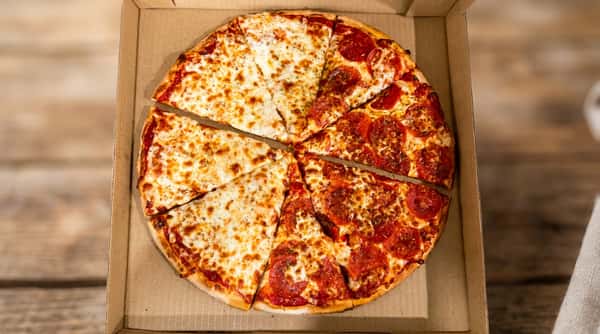 Half cheese and half pepperoni pizza in a cardboard delivery box.