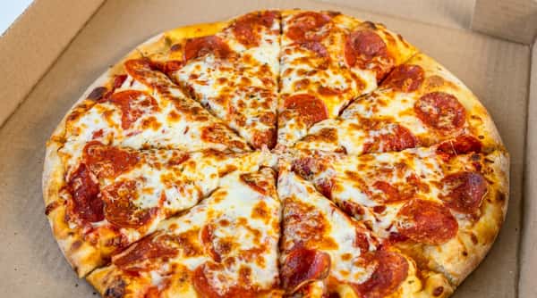 Pepperoni pizza, sliced into eight pieces, with melted cheese and a golden crust in a cardboard box.