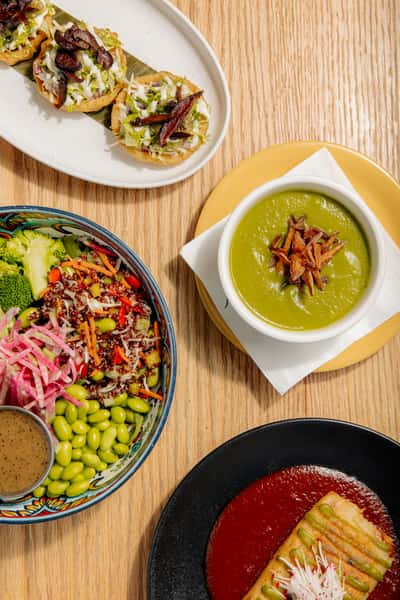 colorful assortment of fresh salads and green soup served in modern bowls on a wooden table