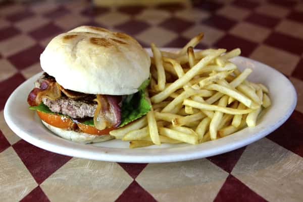 a burger with bacon, lettuce, tomato and a side of fries