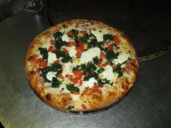 a pizza pie with spinach, tomato and mozzarella